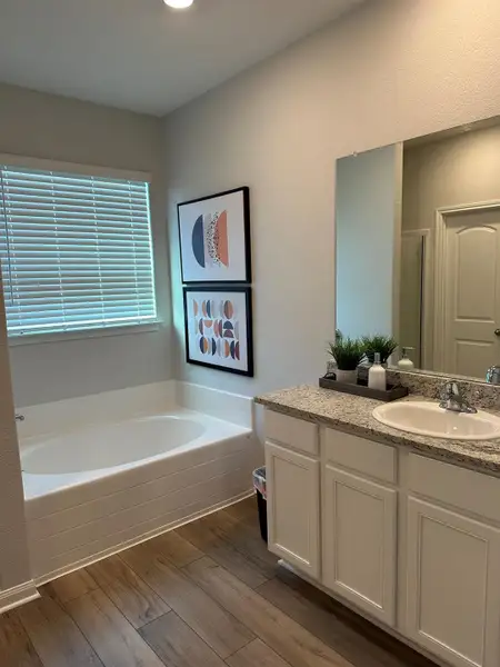 Primary bathroom includes vinyl plank flooring, granite countertops with a garden tub and separate shower.Pictures, floor plans, features, and colors are approximate for illustration purposes only. Home pictured may display decorative items, furniture and enhanced interior paint which are not available for purchase even upon additional payment.