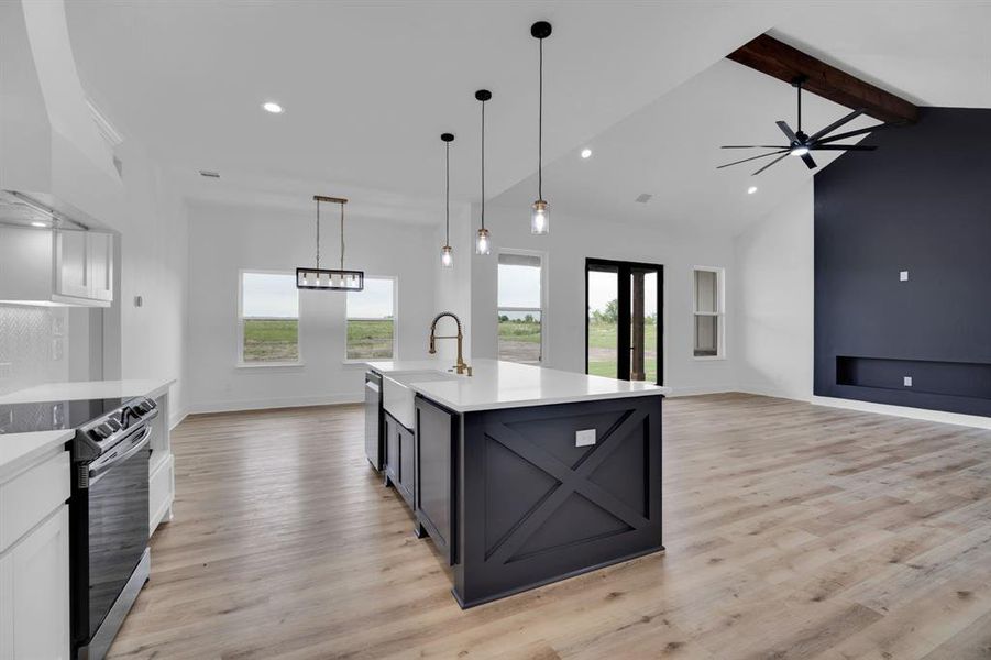 Kitchen featuring light hardwood / wood-style flooring, white cabinetry, custom range hood, decorative light fixtures, and stainless steel appliances