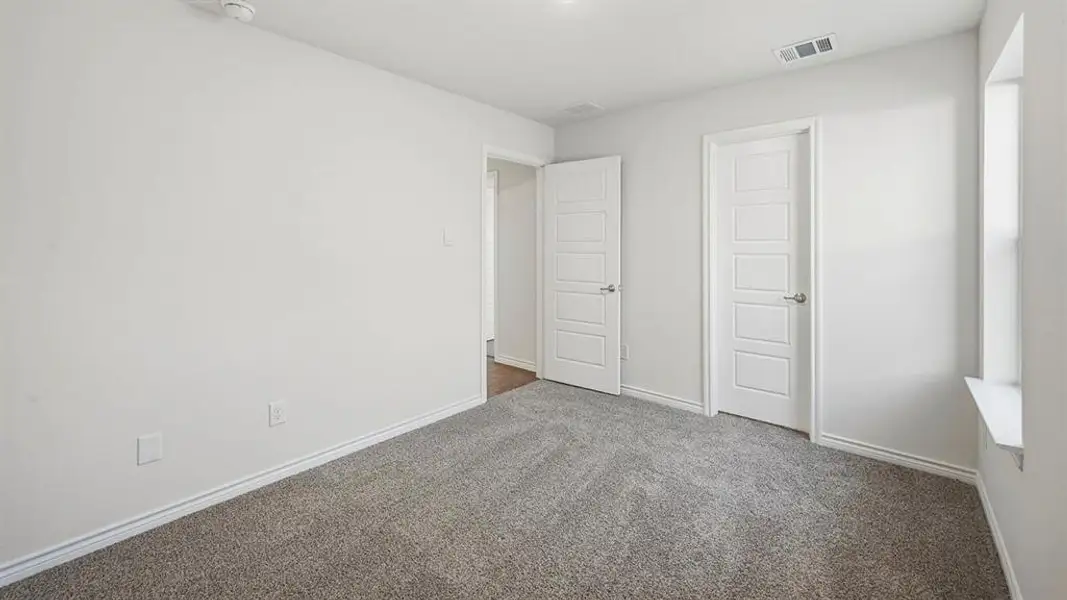 Bright room featuring a window with a deep sill, light gray carpet, and two white panel doors