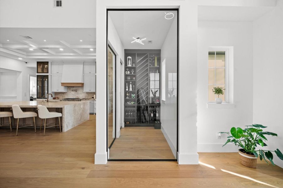 Glass-enclosed wine room creates a striking architectural feature while showcasing your collection.