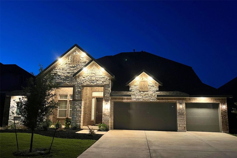 French country inspired facade with concrete driveway, stone siding, an attached garage, and a yard French country inspired facade with concrete driveway, stone siding, an attached garage, and a yard