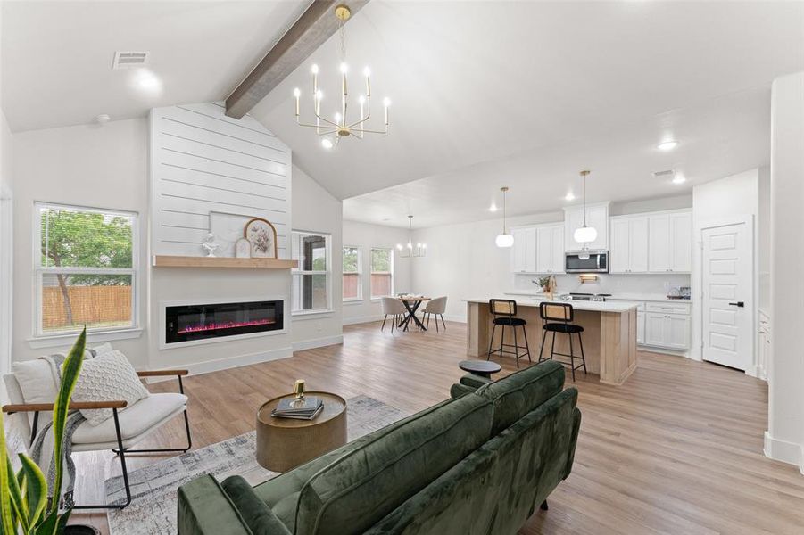 Living area featuring a chandelier, light wood-style floors, a glass covered fireplace, baseboards, and recessed lighting Living area featuring a chandelier, light wood-style floors, a glass covered fireplace, baseboards, and recessed lighting