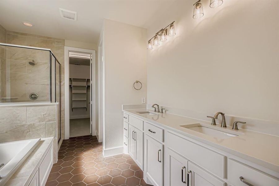 Bathroom with double vanity, dark tile patterned floors, a stall shower, a garden tub, and a walk in closet Bathroom with double vanity, dark tile patterned floors, a stall shower, a garden tub, and a walk in closet