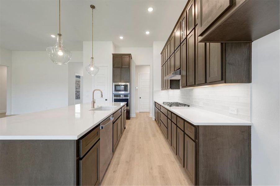 Kitchen featuring a large central island with a built-in sink and two pendant lights Kitchen featuring a large central island with a built-in sink and two pendant lights