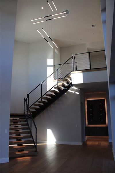 Staircase with a chandelier and hardwood / wood-style floors