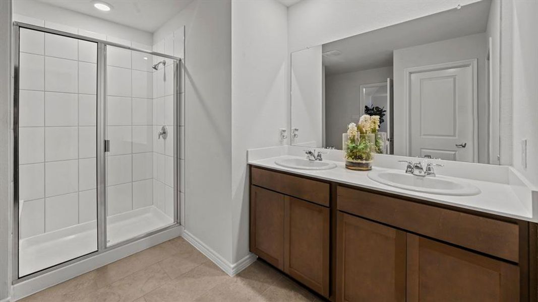 Bathroom featuring a stall shower, double vanity, recessed lighting, and light tile patterned flooring