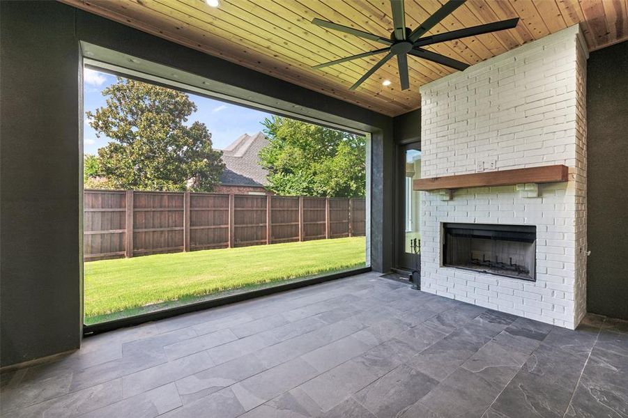 Unfurnished sunroom with an outdoor brick fireplace, wooden ceiling, and ceiling fan