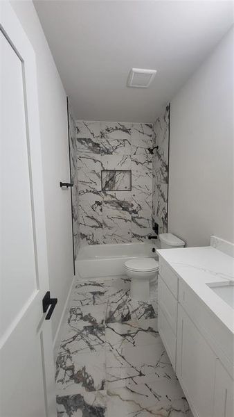 Bathroom featuring marble finish floor, visible vents, toilet, vanity, and tub / shower combination