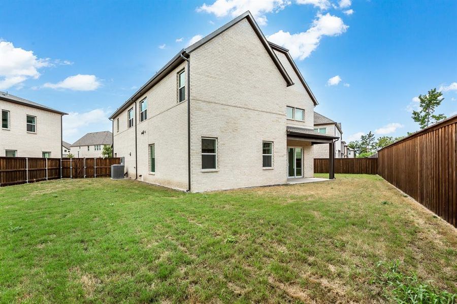 Back of house featuring central AC, a lawn, and a patio