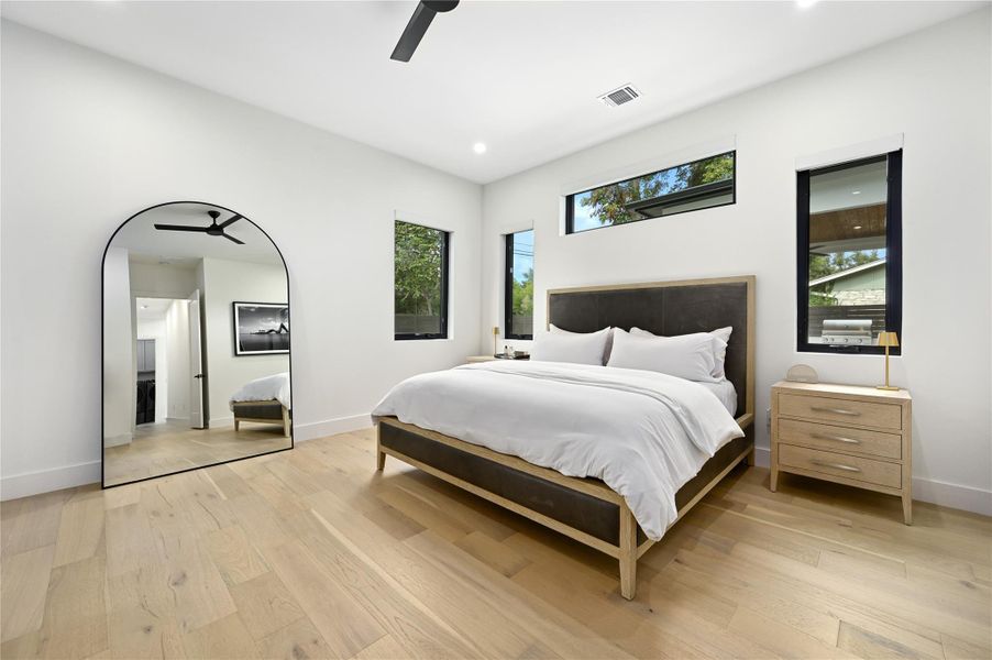 Bedroom featuring visible vents, baseboards, light wood-style floors, and ceiling fan