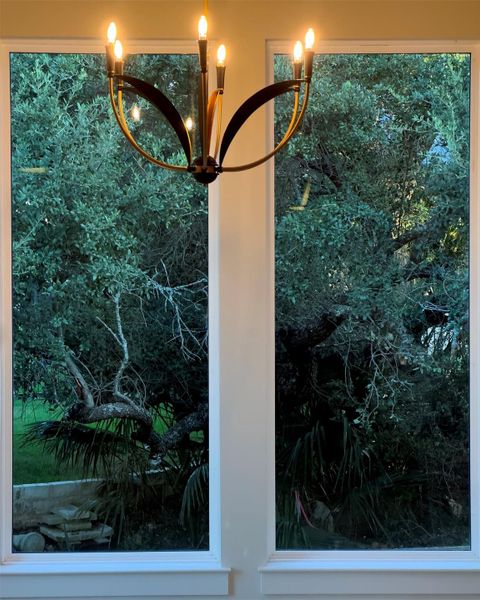Large picture windows frame serene views of lush, mature trees. Large picture windows frame serene views of lush, mature trees.