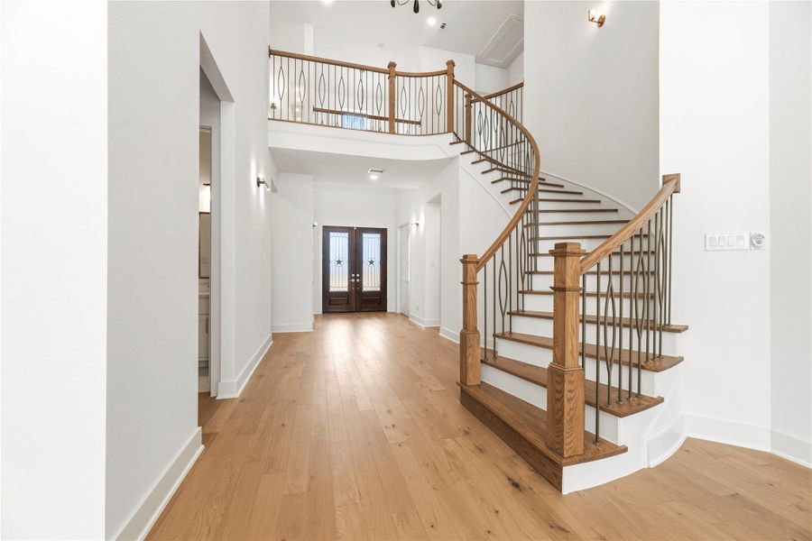 A dramatic formal entry welcomes you with a breathtaking spiral staircase, ornate iron detailing, and rich wood flooring, establishing a sophisticated tone for this refined residence.