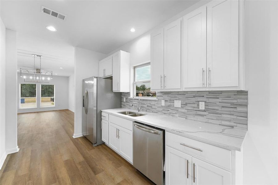 Kitchen with white shaker-style cabinetry, stainless steel appliances, and light-toned countertops