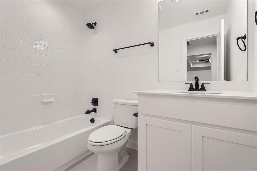 Full bathroom with vanity, toilet, tile patterned flooring, and tiled shower / bath