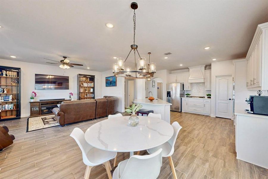 Dining room with a chandelier, wood tiled floors, a fireplace, arched walkways, and recessed lighting