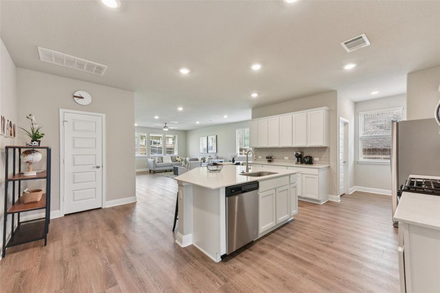 Kitchen featuring a kitchen island with sink, appliances with stainless steel finishes, white cabinets, light countertops, and recessed lighting Kitchen featuring a kitchen island with sink, appliances with stainless steel finishes, white cabinets, light countertops, and recessed lighting