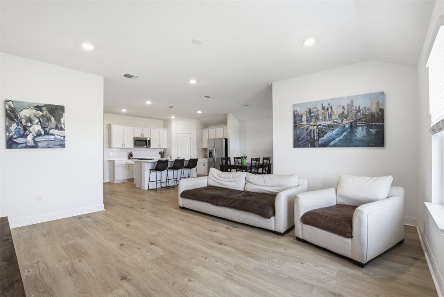 Open-concept living area featuring wood-finish flooring and recessed lighting