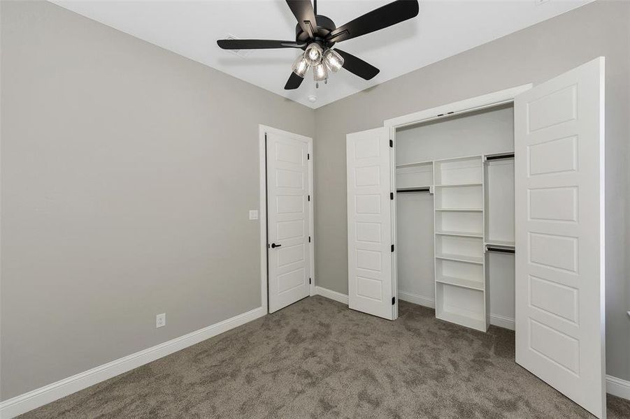 Unfurnished bedroom with carpet, a closet, and a ceiling fan