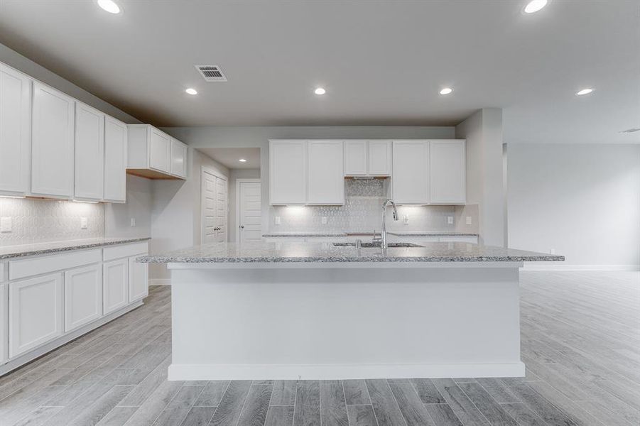 Discover another perspective of this stunning kitchen, generously appointed with an abundance of counter space. Sample photo of completed home with similar floor plan. As-built interior colors and selections may vary.