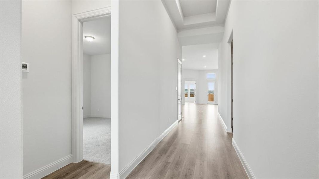 Hallway with wood-finish flooring extending into a bright interior space