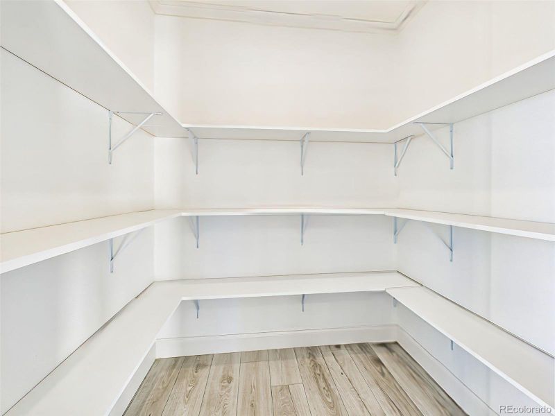Walk-in pantry with wraparound shelving for ample kitchen storage and organization. Walk-in pantry with wraparound shelving for ample kitchen storage and organization.