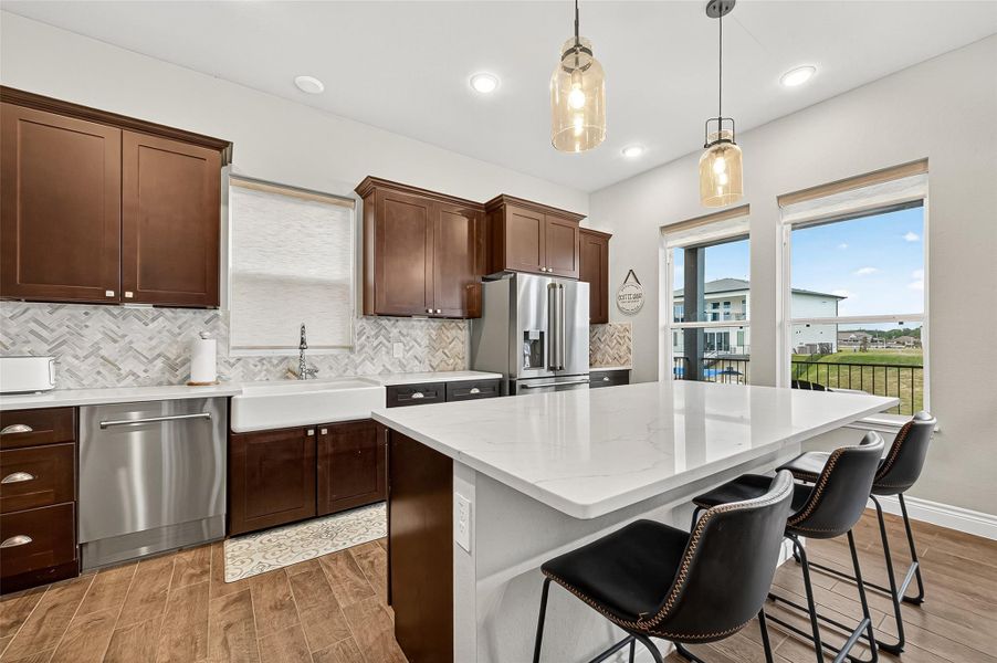 Gourmet kitchen with upgraded stainless-steel appliances, deep farmhouse sink, and herringbone tile backsplash. Large quartz island offers extra prep space and casual dining with lake views from surrounding windows. Gourmet kitchen with upgraded stainless-steel appliances, deep farmhouse sink, and herringbone tile backsplash. Large quartz island offers extra prep space and casual dining with lake views from surrounding windows.