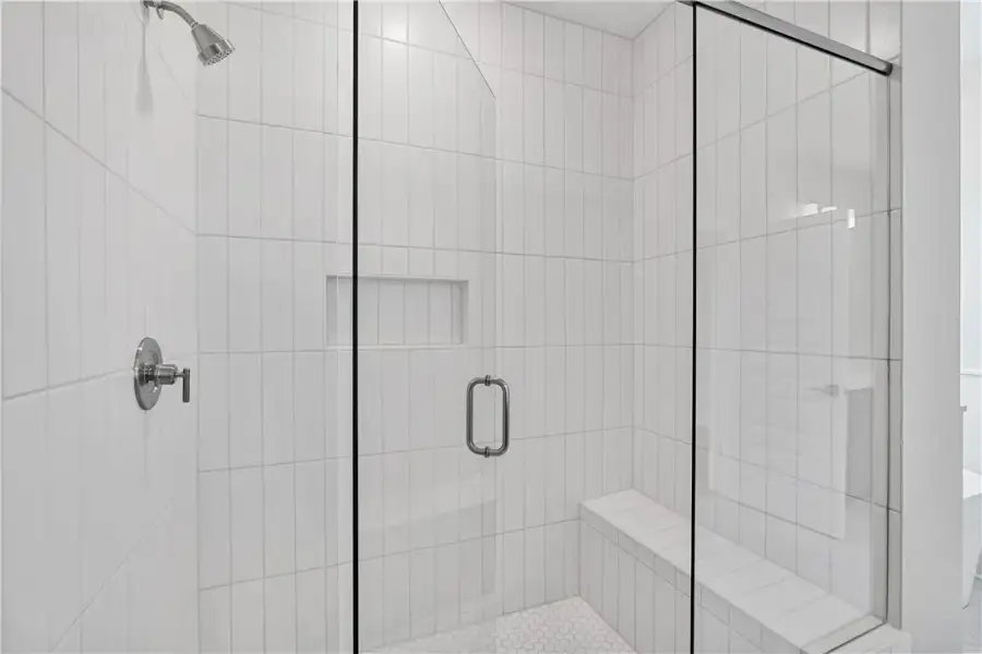 A pristine shower with white tiled walls and hexag A pristine shower with white tiled walls and hexag