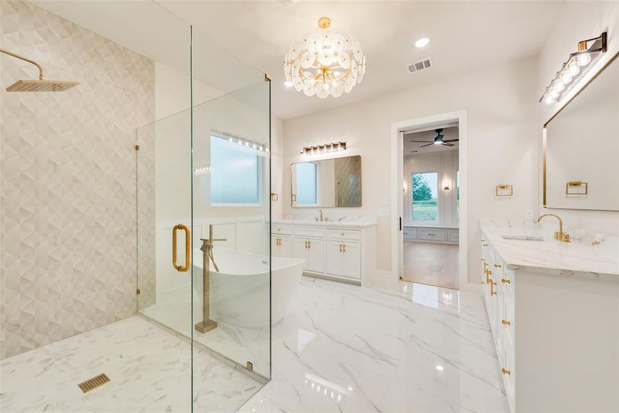 Full bathroom with a shower stall, two vanities, a freestanding tub, a chandelier, and marble finish flooring Full bathroom with a shower stall, two vanities, a freestanding tub, a chandelier, and marble finish flooring