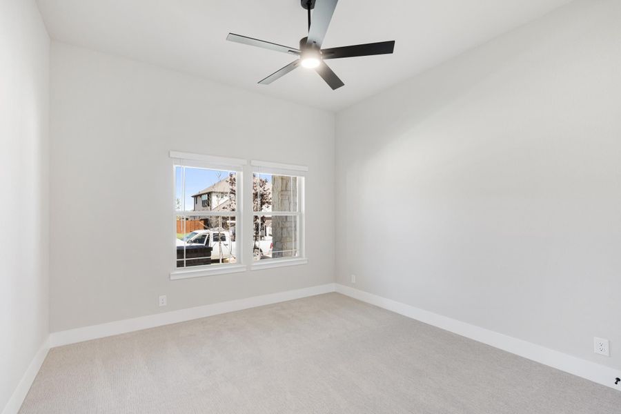 Empty bedroom with light carpet, white walls, ceiling fan, and a double window