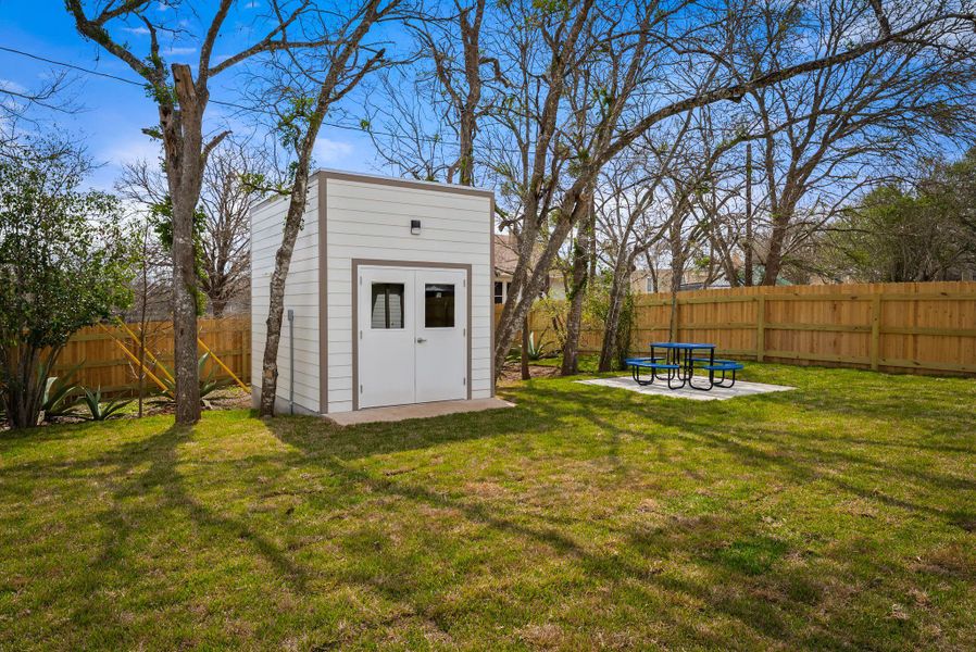 Fenced backyard featuring a patio and an outbuilding