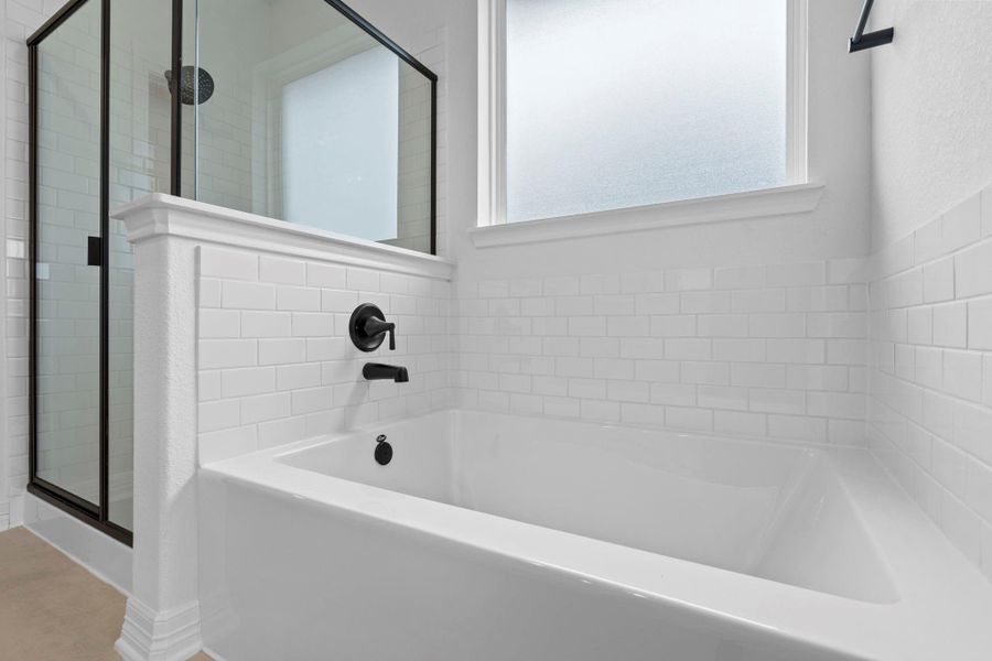 This additional view of your primary bathroom features tile flooring, fresh paint, walk-in shower, a separate garden tub, and a large walk-in closet.