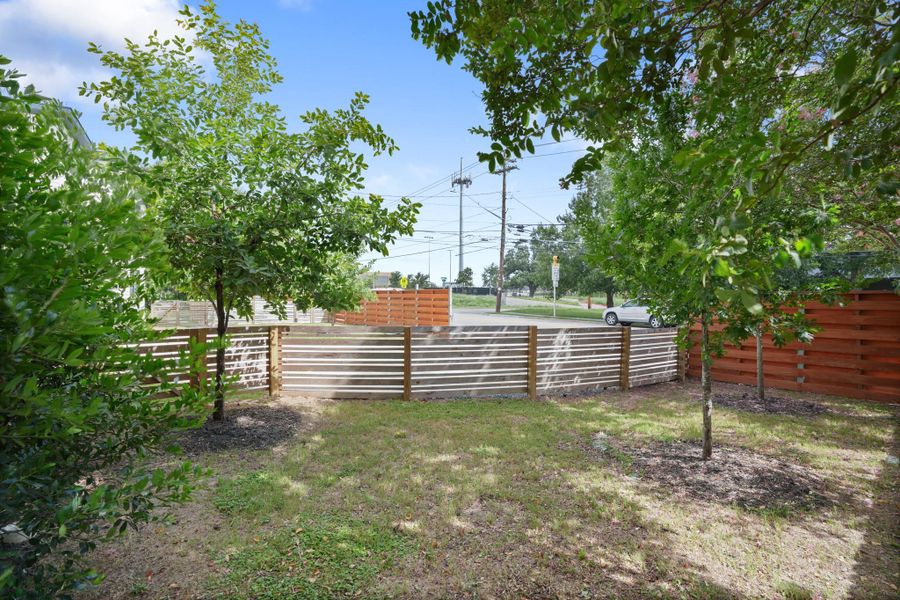 A well-maintained yard, bordered by a stylish horizontal slat fence, offers privacy and natural beauty. A well-maintained yard, bordered by a stylish horizontal slat fence, offers privacy and natural beauty.