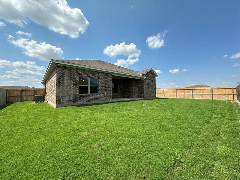 Back of property with a fenced backyard, a patio area, brick siding, and a shingled roof
