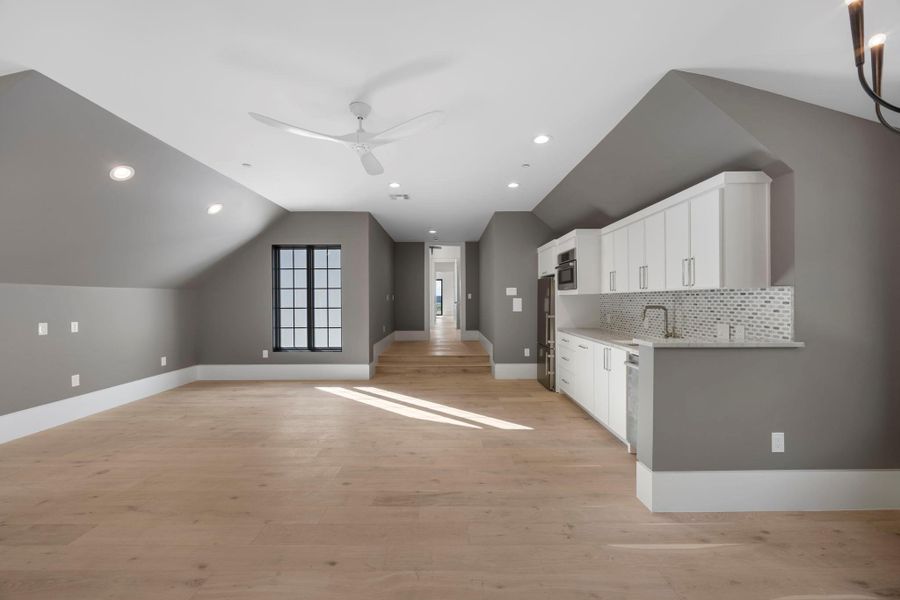 A grand entertainment room with soaring vaulted ceilings, recessed lighting, and a modern kitchen space. A grand entertainment room with soaring vaulted ceilings, recessed lighting, and a modern kitchen space.