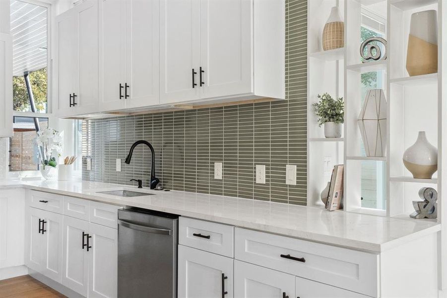 Kitchen featuring light stone countertops, white cabinets, stainless steel dishwasher, decorative backsplash, and light wood-type flooring