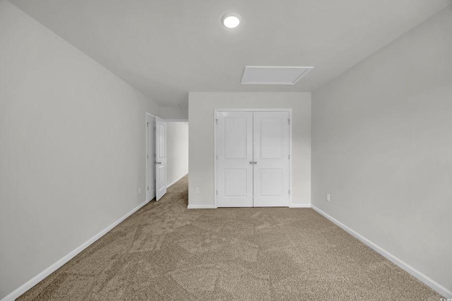 Unfurnished bedroom with carpet floors, a closet, and attic access Unfurnished bedroom with carpet floors, a closet, and attic access