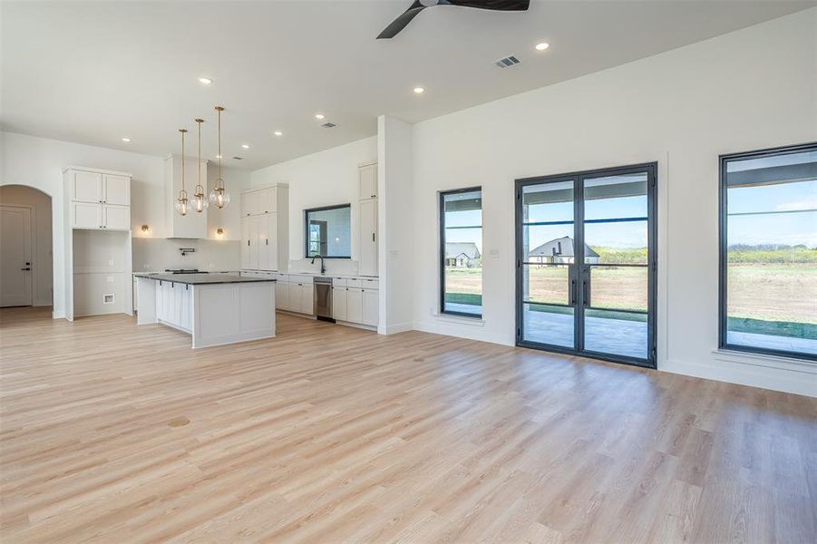 Kitchen featuring a kitchen island, light hardwood / wood-style floors, decorative light fixtures, white cabinets, and ceiling fan with notable chandelier