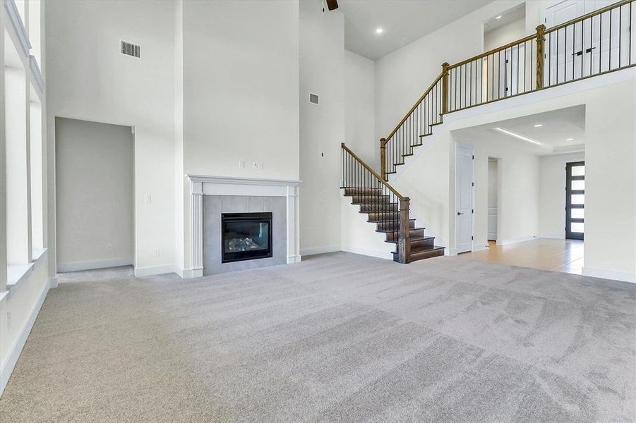 Two-story living area featuring a central fireplace with a light gray surround and white mantel Two-story living area featuring a central fireplace with a light gray surround and white mantel
