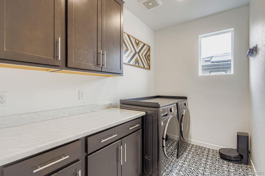 The well-appointed laundry room showcases custom tile flooring and substantial cabinetry for added storage and organization.