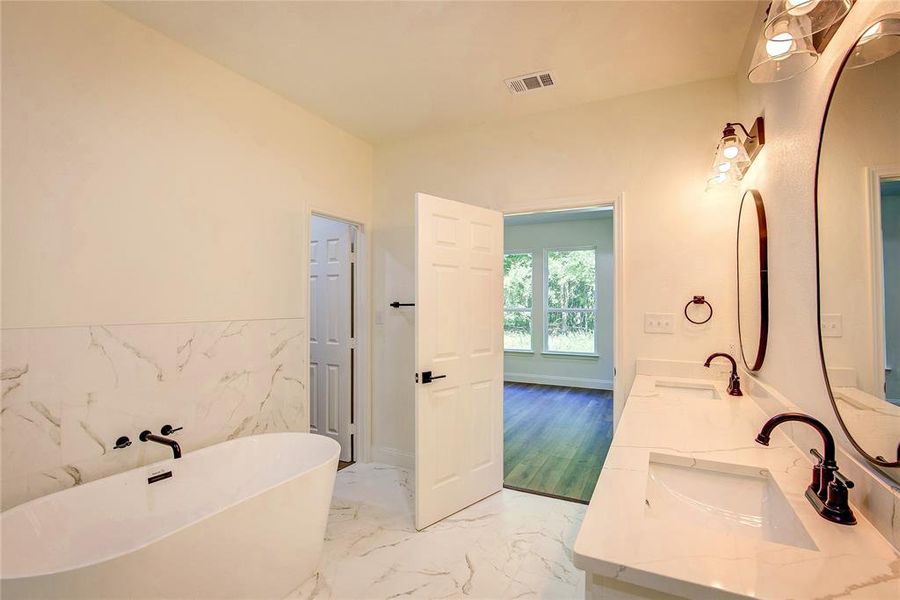 Bathroom with a freestanding tub, double vanity, a wainscoted wall, tile walls, and marble finish floors Bathroom with a freestanding tub, double vanity, a wainscoted wall, tile walls, and marble finish floors