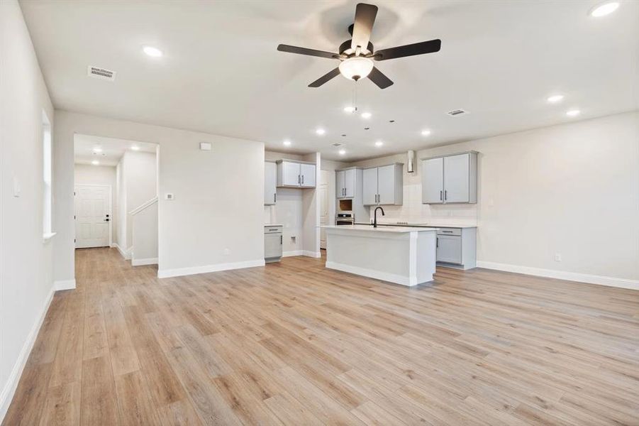 Unfurnished living room featuring ceiling fan, sink, and light hardwood / wood-style floors