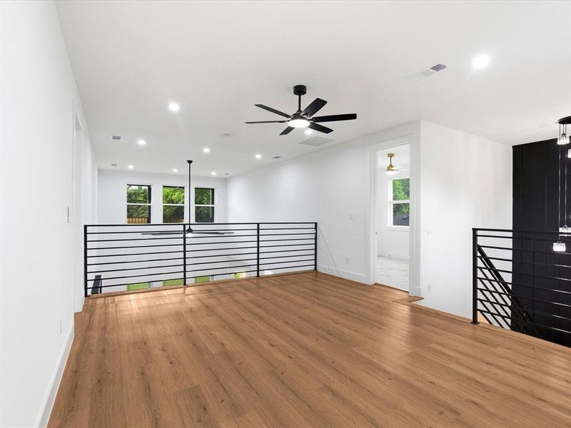Open loft space featuring wood-finish flooring, white walls, and recessed lighting