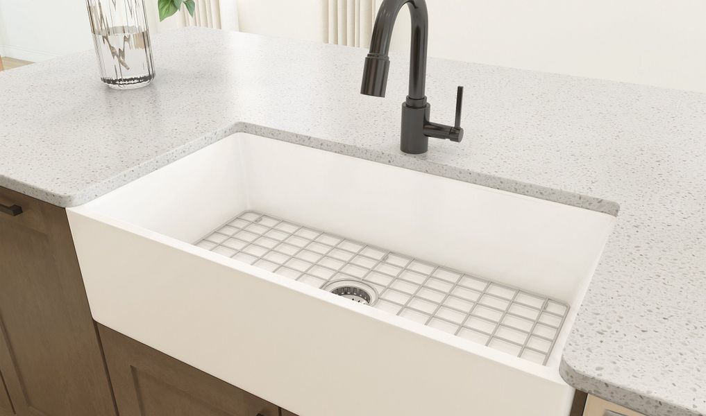 White apron front sink within the kitchen featuring matte black faucets