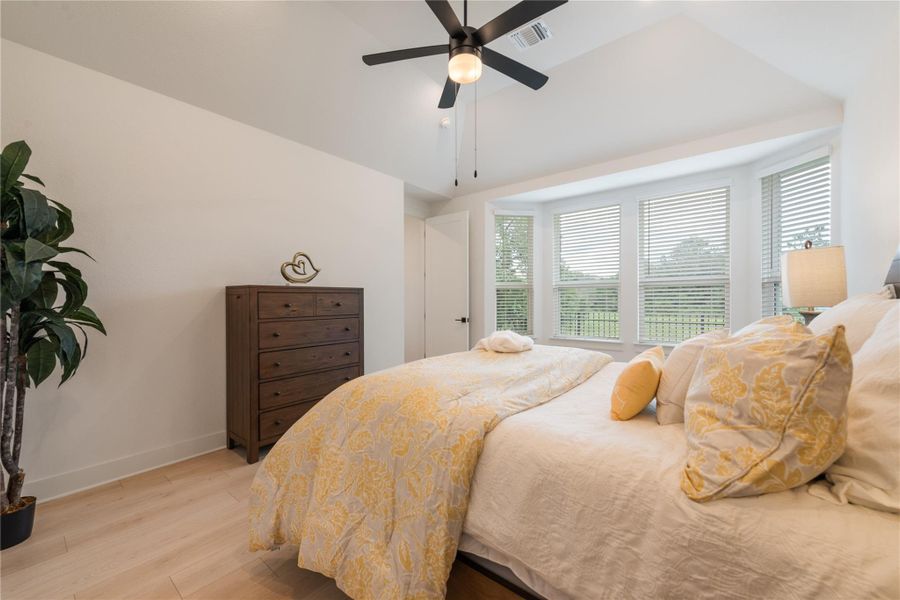 A tranquil bedroom retreat features bay windows overlooking natural surroundings and a welcoming ambiance. A tranquil bedroom retreat features bay windows overlooking natural surroundings and a welcoming ambiance.