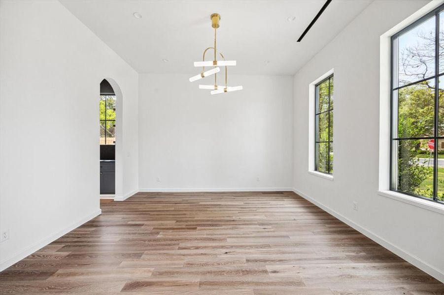 Formal dining room with a Visual Comfort chandelier, two large windows facing the front providing ample light, and an arched doorway leading to the adjacent butler's pantry