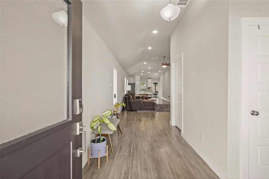 Step inside to a welcoming entryway highlighted by soaring ceilings, recessed lighting, and durable wood-look flooring that flows throughout the main living areas. The long foyer creates an inviting first impression and opens into a bright open-concept living space with abundant natural light and modern finishes. Clean lines and neutral tones provide the perfect backdrop for any décor style while enhancing the home’s spacious feel.