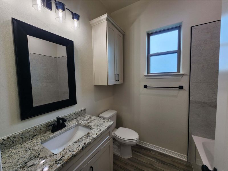 Bathroom featuring a contemporary vanity with a granite countertop, undermount sink, and matte black faucet