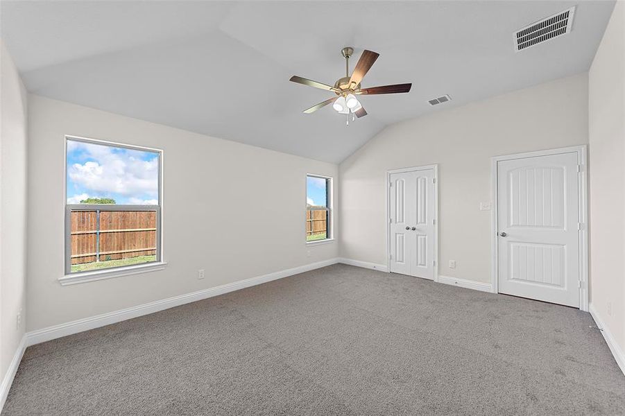 Unfurnished bedroom featuring ceiling fan, vaulted ceiling, and carpet floors