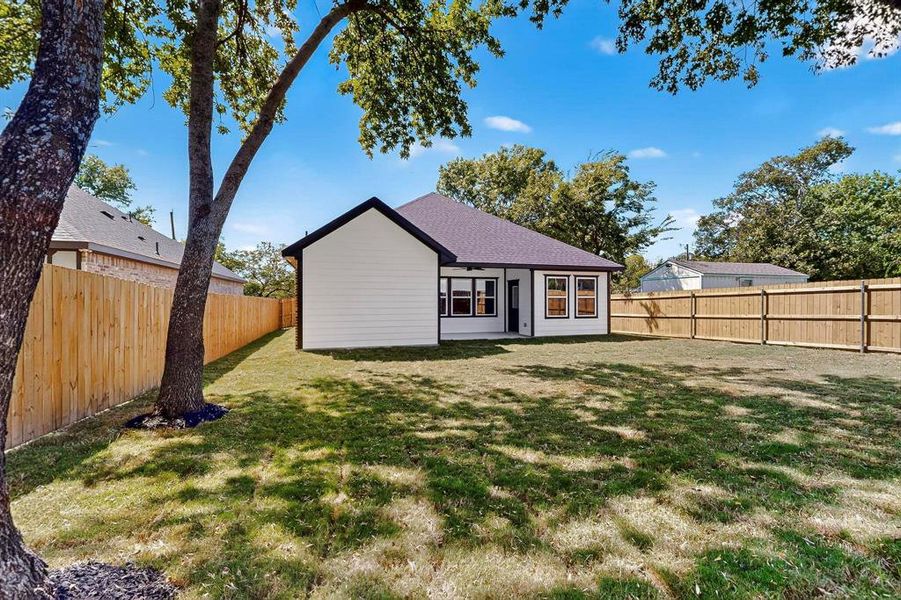 Back of property with a fenced backyard, a shingled roof, and a patio area