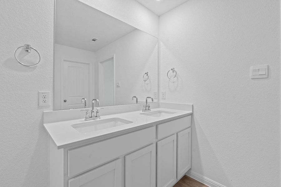 Bathroom featuring a textured wall and double vanity Bathroom featuring a textured wall and double vanity